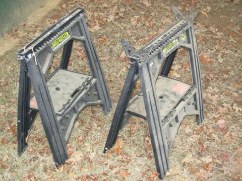 2004 Land Rover Land Rover - Two black sawhorses are shown outdoors on a bed of fallen leaves. Each sawhorse has a yellow label that reads "STOREHORSE".