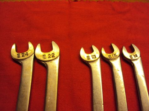1965 Ford Mustang - A collection of five metric wrenches, labeled E24, E22, E18, E16, and E14, are laid out on a red fabric surface.