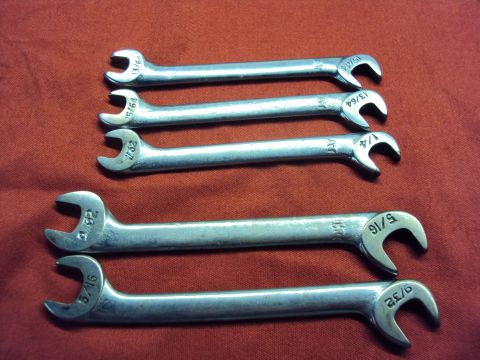 1965 Ford Mustang - Six combination wrenches are laid out on a red textured surface, showing various fractional inch sizes.