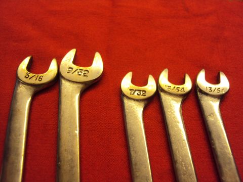 1965 Ford Mustang - A collection of five wrenches, each marked with its size in fractions of an inch, laid out on a red surface.