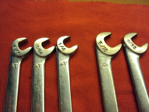 1965 Ford Mustang - A collection of assorted wrenches, including sizes 15/64, 13/64, 1/4, 5/16, and 9/32, are displayed on a red surface.