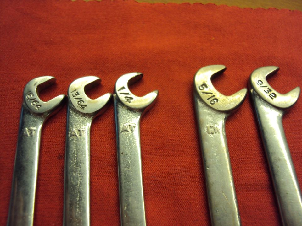 Five metal wrenches with fractional and decimal inch markings, laid out on a red cloth