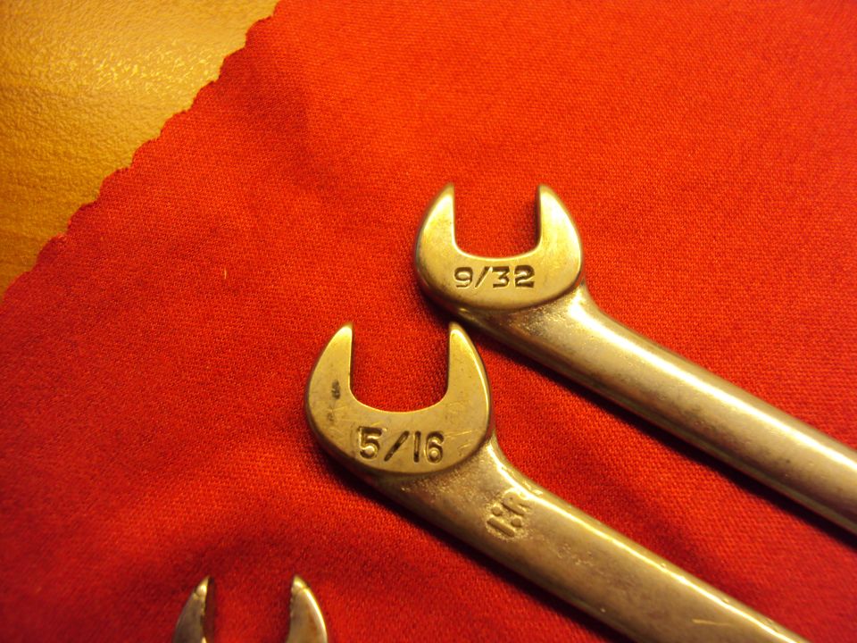Two combination wrenches, one marked 9/32 and the other 5/16, lie on a red cloth