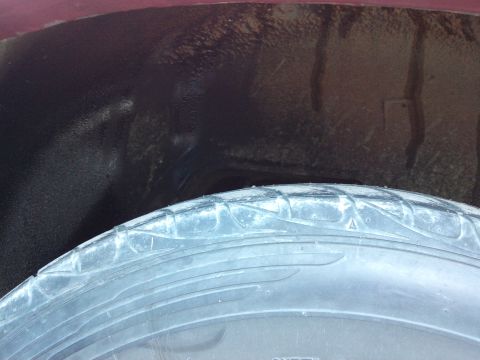 1998 Ford Crown Victoria - Close-up view of a vehicle's wheel well interior, showing the tire and undercoating.
