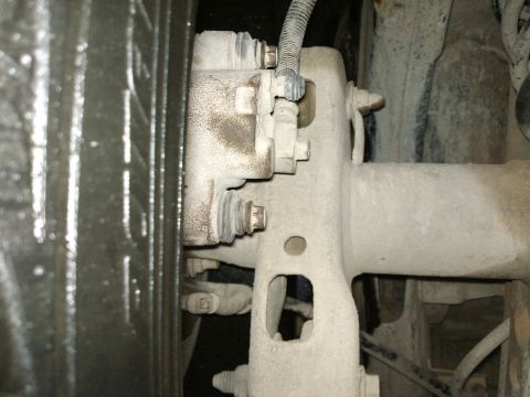 1998 Ford Crown Victoria - A close-up view of a vehicle's rear axle and brake components, showing dust and wear.