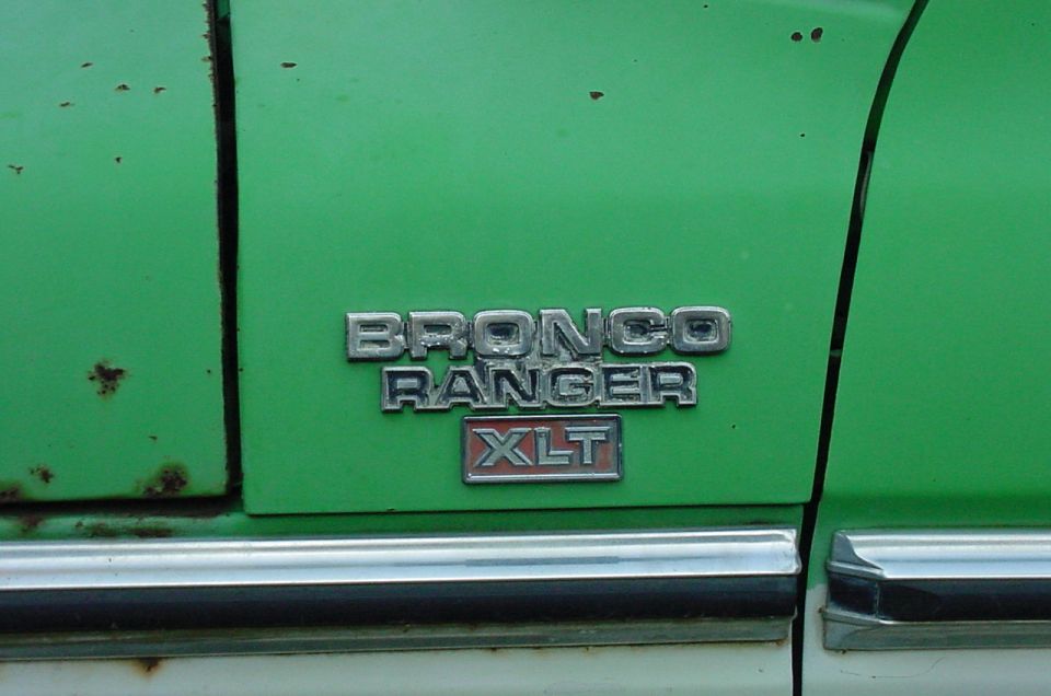 Close-up of a green vehicle's side panel showing a 'BRONCO RANGER XLT' emblem. Some rust spots are visible