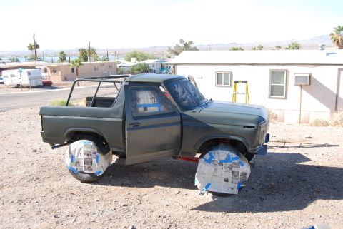 1982 Ford Bronco - Ford Bronco undergoing preparation for a paint job, with wheels covered and doors ajar.