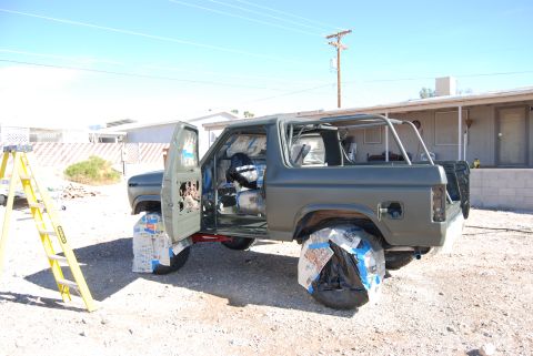 1982 Ford Bronco - SUV undergoing preparation for painting, with doors open and wheels covered.