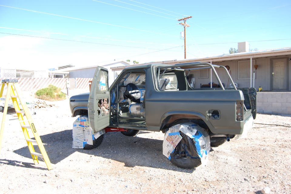 Gray SUV with doors open, wheels covered, and roll cage visible
