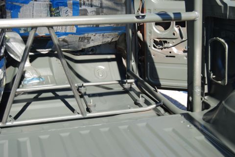 1982 Ford Bronco - The interior of a vehicle is shown with a roll cage, and the door is open, revealing the door frame and masking paper.