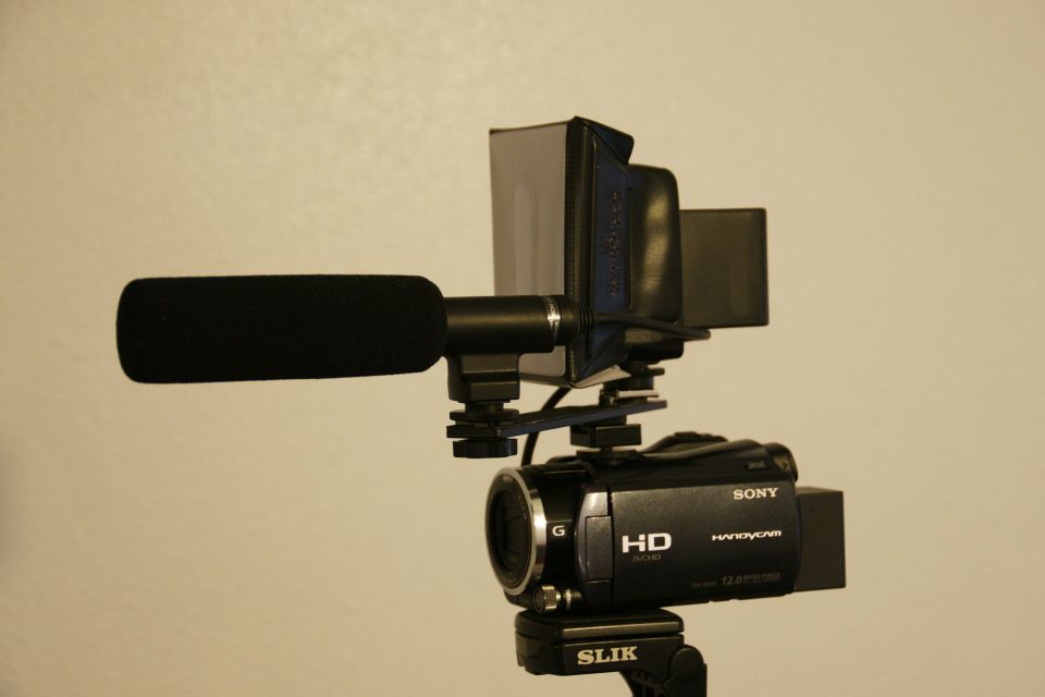 Sony Handycam camcorder with external microphone and sunshade attached to tripod