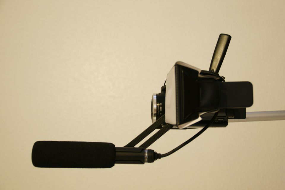 Video camera with foam-covered microphone attached, mounted on a pole
