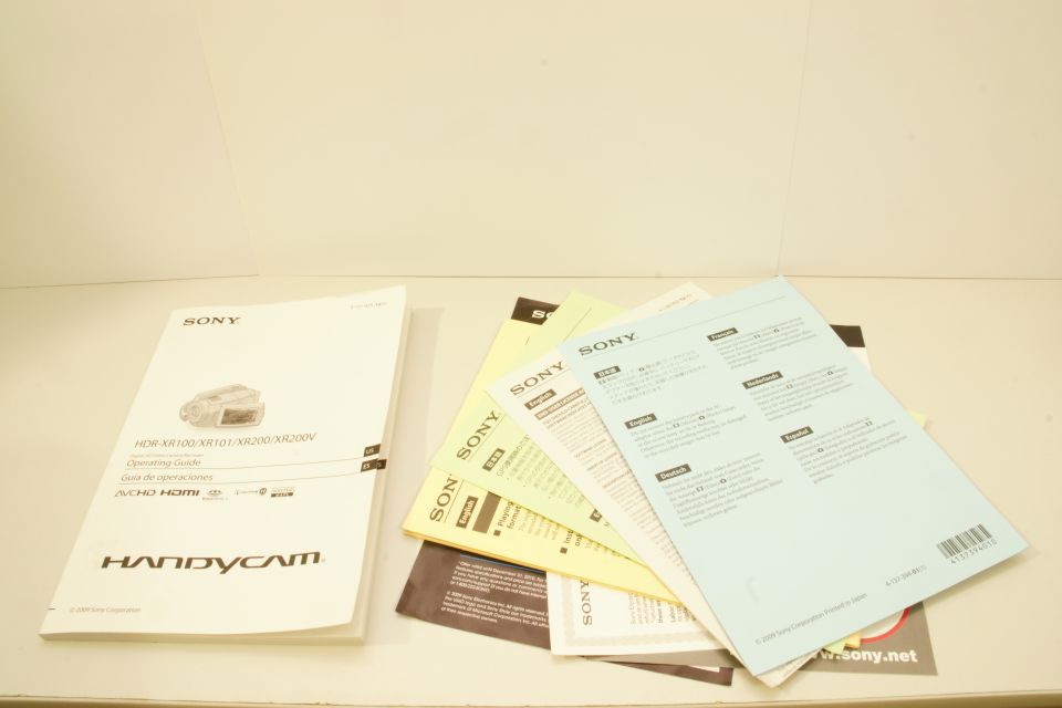 Stack of Sony Handycam operating guides, one open showing a camcorder illustration and text