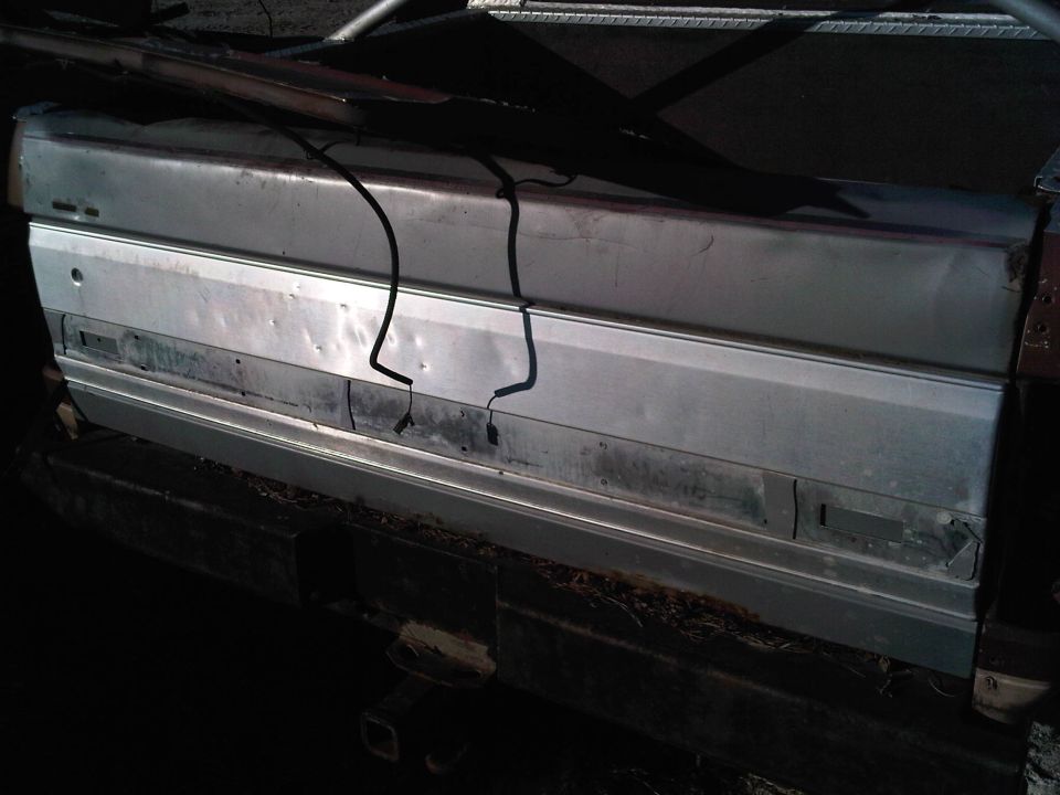 Damaged silver vehicle side panel with black wires attached