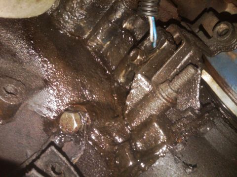 1982 Ford Bronco - Greasy engine components are visible in this close-up view, with a wire connected to a sensor.