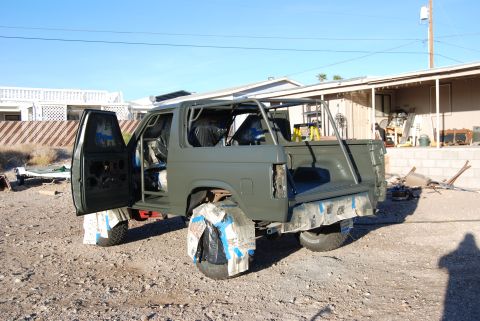 1982 Ford Bronco - This olive green SUV, possibly undergoing restoration, features an exposed interior and a prominent roll cage.