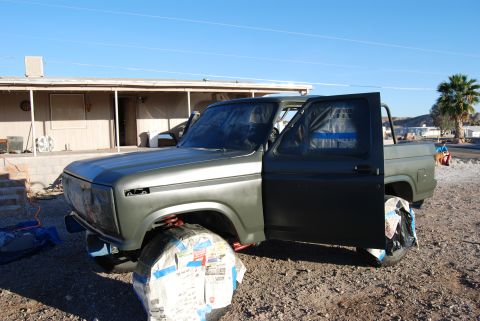 1982 Ford Bronco - Ford Bronco is prepped for a new paint job, with wheels covered and doors open.