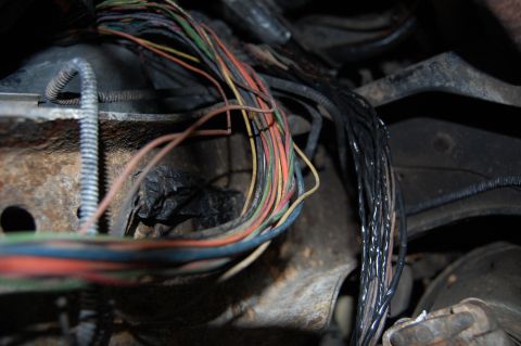 1994 Ford Bronco - A close-up view shows a damaged wiring harness with many frayed wires and evidence of black tape, suggesting a repair or damage.