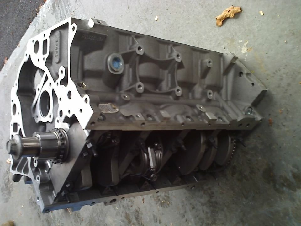 Engine block with crankshaft visible, on concrete floor