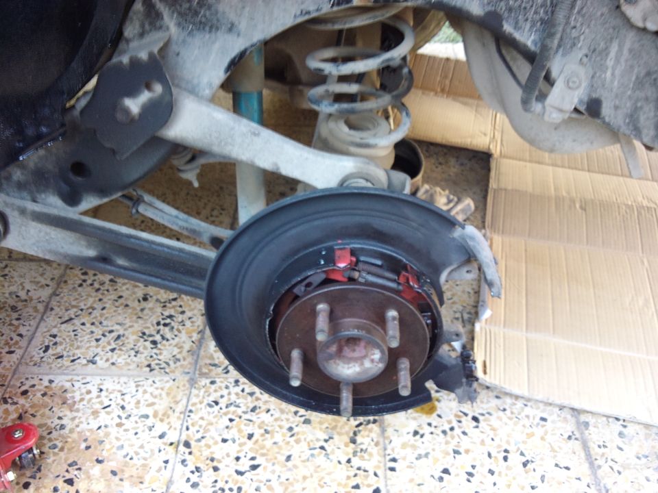Rear axle assembly with brake drum removed, showing brake shoes and rotor. Some rust and wear visible