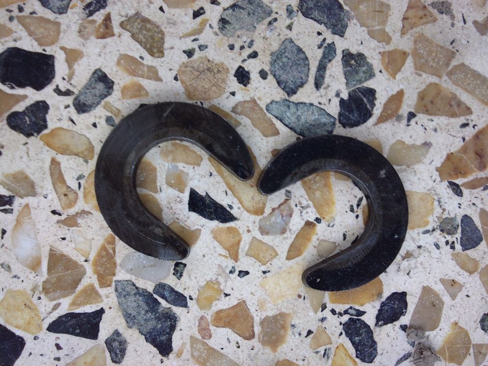 two C-shaped metal parts on a terrazzo floor