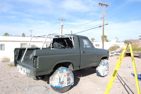 1982 Ford Bronco - A Ford Bronco is parked outside with its wheels covered in newspaper, likely for painting.