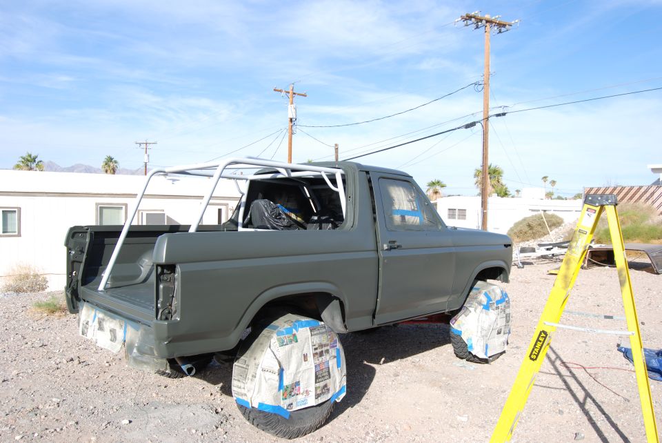 Ford Bronco with roll cage, wheels covered in newspaper, ready for paint