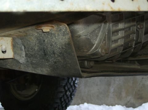 1986 Ford F-150 - Close-up of the underside of a vehicle, focusing on the transmission and frame components.