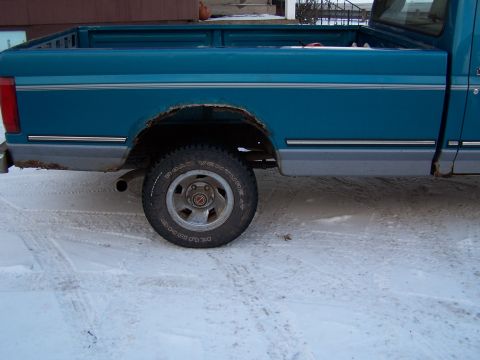 1994 Ford F-150 - Side view of a 1994 Ford F-150 pickup truck in the snow, with visible rust on the rear wheel arch.