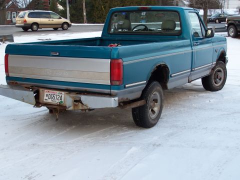 1994 Ford F-150 - The rear of a blue Ford F-150 pickup truck is shown parked in the snow.