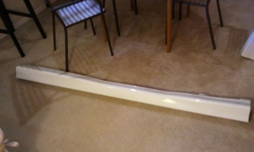 White car side skirt on carpeted floor, with chairs and table legs in background
