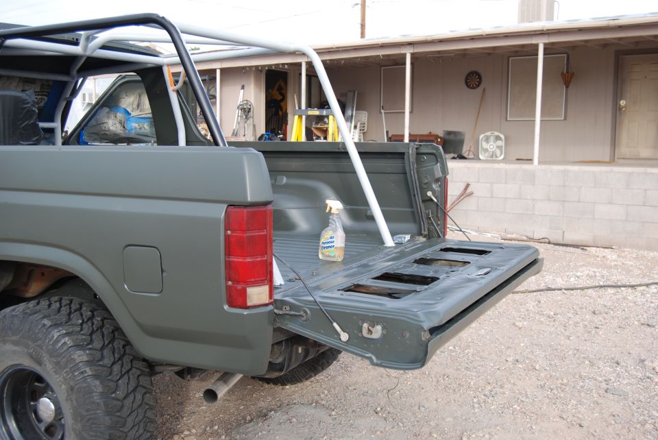 Gray Ford Bronco with tailgate down, roll cage, and spray bottle in bed
