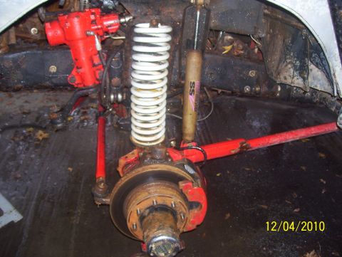 1978 Ford Bronco - Close-up of vehicle suspension components, including a red steering box and white coil spring.
