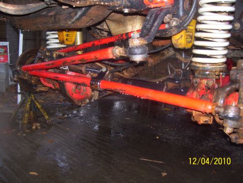 1978 Ford Bronco - Close-up view of the undercarriage suspension system, showing red painted components and white coil springs.