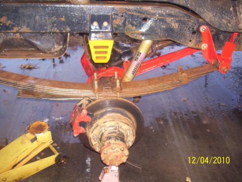 1978 Ford Bronco - Vehicle suspension and brake components are shown in this close-up image, with a yellow jack in view.