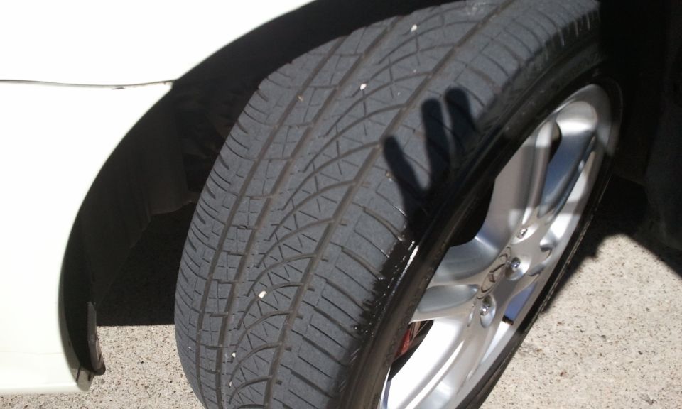 Close-up of tire tread and silver alloy wheel on white car