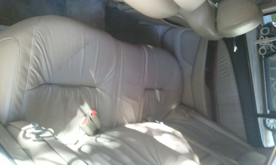 Tan leather rear bench seat inside a sedan, photo rotated sideways