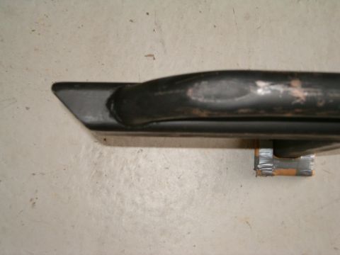 1991 Ford Bronco - A close-up view of a black metal tube with an angled end, secured with tape to a surface.