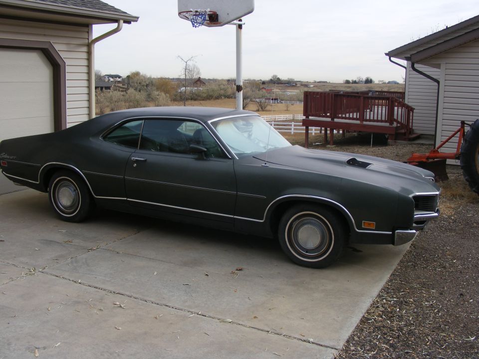 1971 Mercury Cyclone parked in driveway, dark green paint, hood scoop