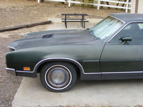 1971 Mercury Cyclone - A dark green coupe with a hood scoop and chrome trim is parked on a concrete driveway.
