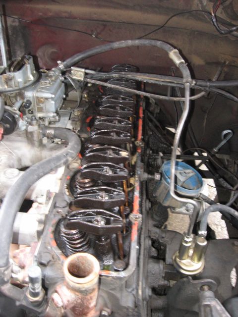 1981 Ford Bronco - Valve cover removed on an in-vehicle V8, exposing oiled rocker arms, valve springs and pushrods along the cylinder head with orange gasket…