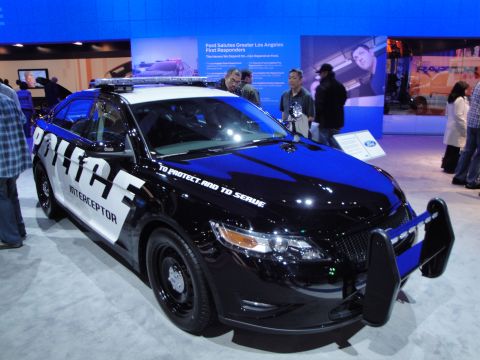 1993 Ford Taurus - A police interceptor car is displayed at an auto show with "To Protect. And To Serve." text on the hood.