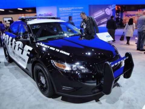 1993 Ford Taurus - A police interceptor car with "To Protect and to Serve" text is displayed at an auto show.