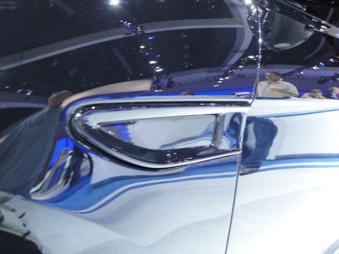 1993 Ford Taurus - Close-up of a car's side panel with chrome accents and a blue stripe, reflecting the surrounding environment.