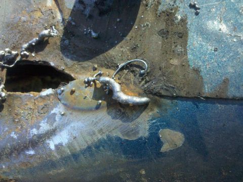 1989 Ford Bronco - This image shows a section of heavily rusted metal that has been welded, revealing a blue painted surface beneath.