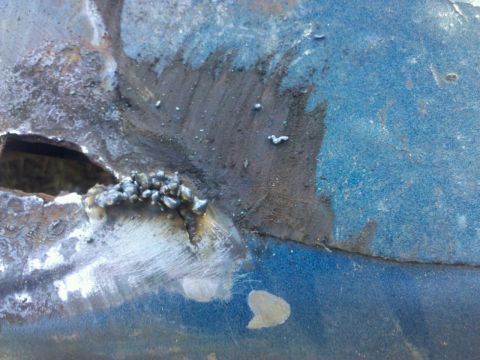 1989 Ford Bronco - This image shows a damaged and repaired section of a blue metal panel, with visible rust and welding.