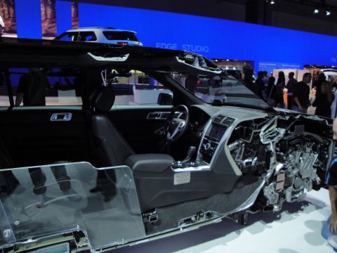 1993 Ford Taurus - A cutaway view of a modern SUV's interior and engine compartment is displayed at an auto show.