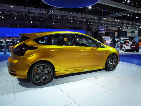 1993 Ford Taurus - A yellow hatchback is displayed at an auto show, with another car visible in the background.
