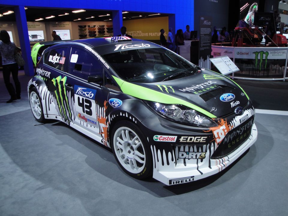 Black Ford Fiesta rally car with green and white Monster Energy graphics, number 43, and Pirelli tires