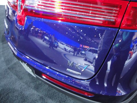 1993 Ford Taurus - Blue Lincoln MKX at an auto show, with reflections of other cars visible on its surface.
